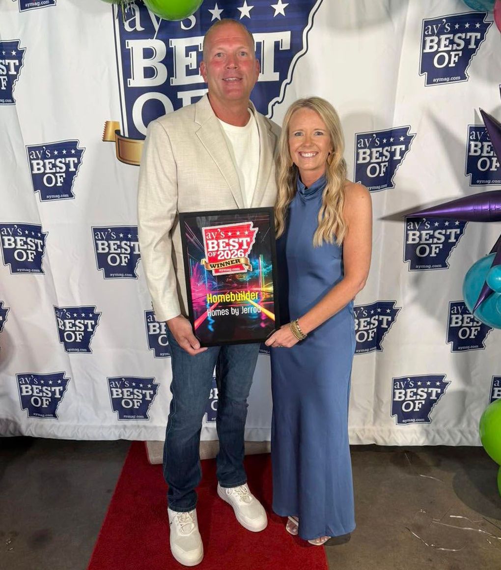 Two people posing at an awards event, holding a colorful plaque