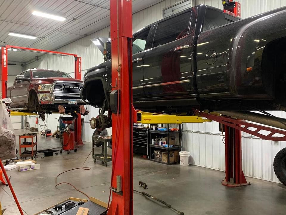 A truck is sitting on a lift in a garage.