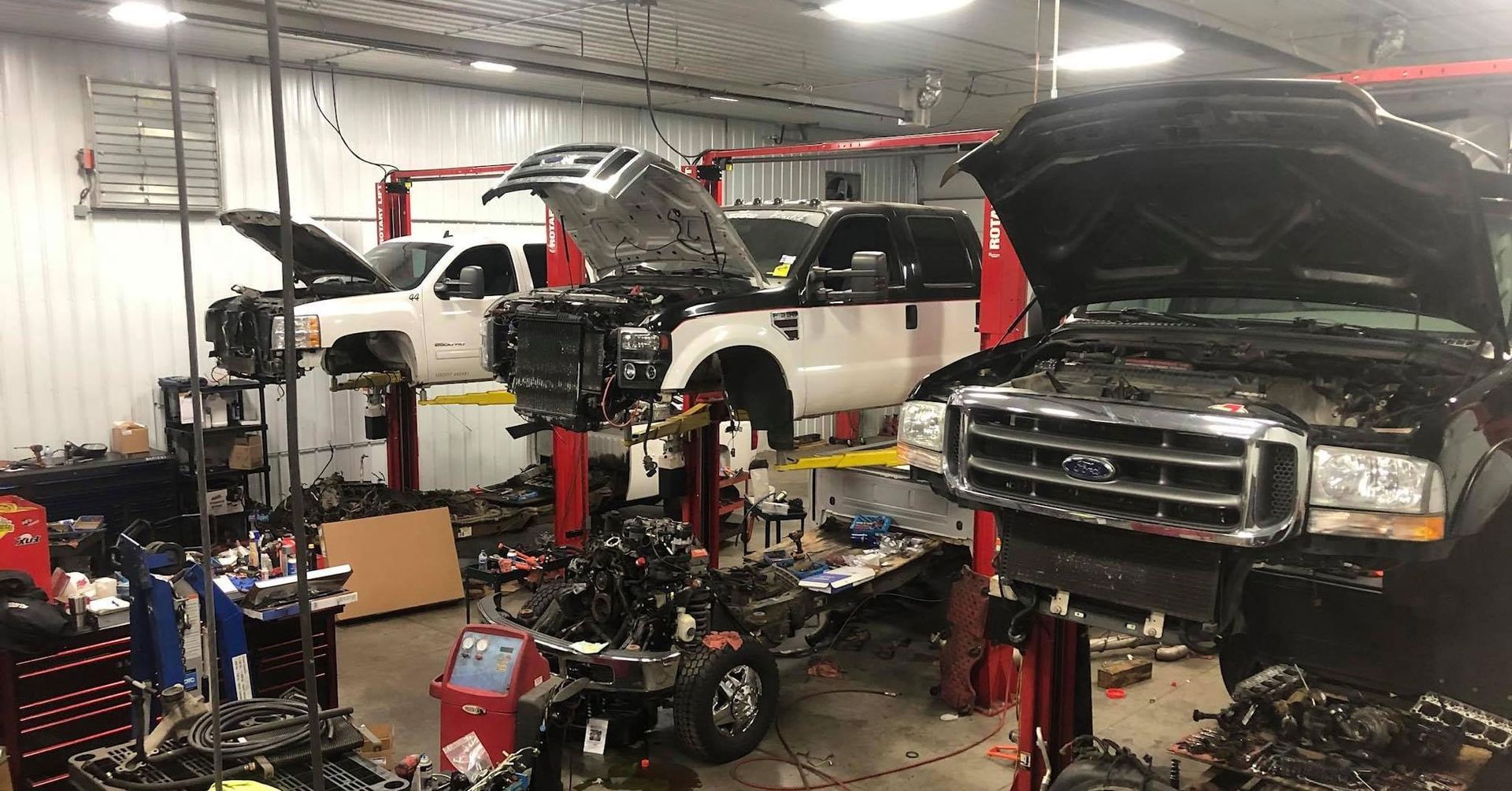 A lot of trucks are being worked on in a garage.
