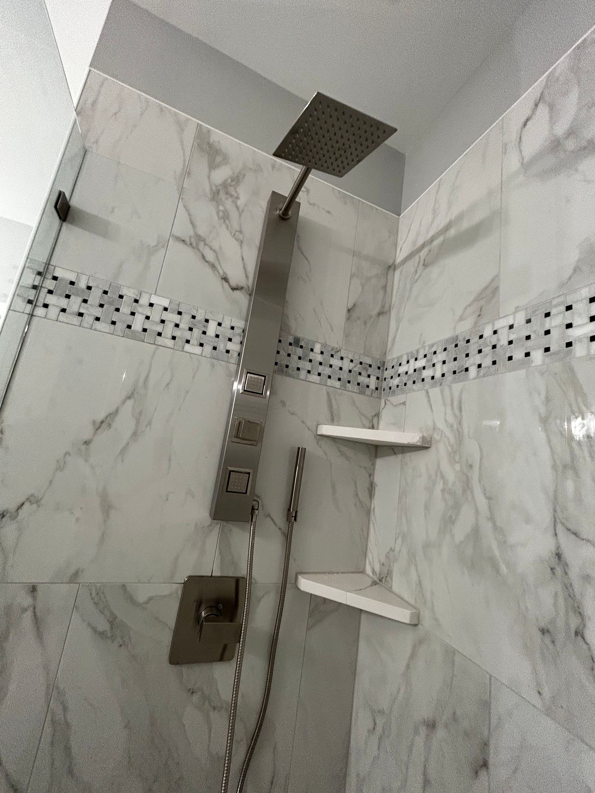 Modern marble-tiled shower with rainfall head, handheld shower, and two corner shelves