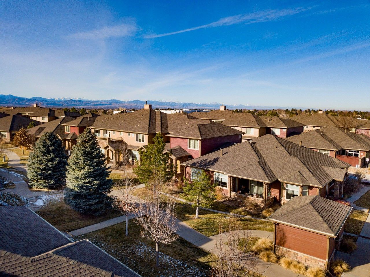 Suburban neighborhood with rows of houses and trees under a clear blue sky.