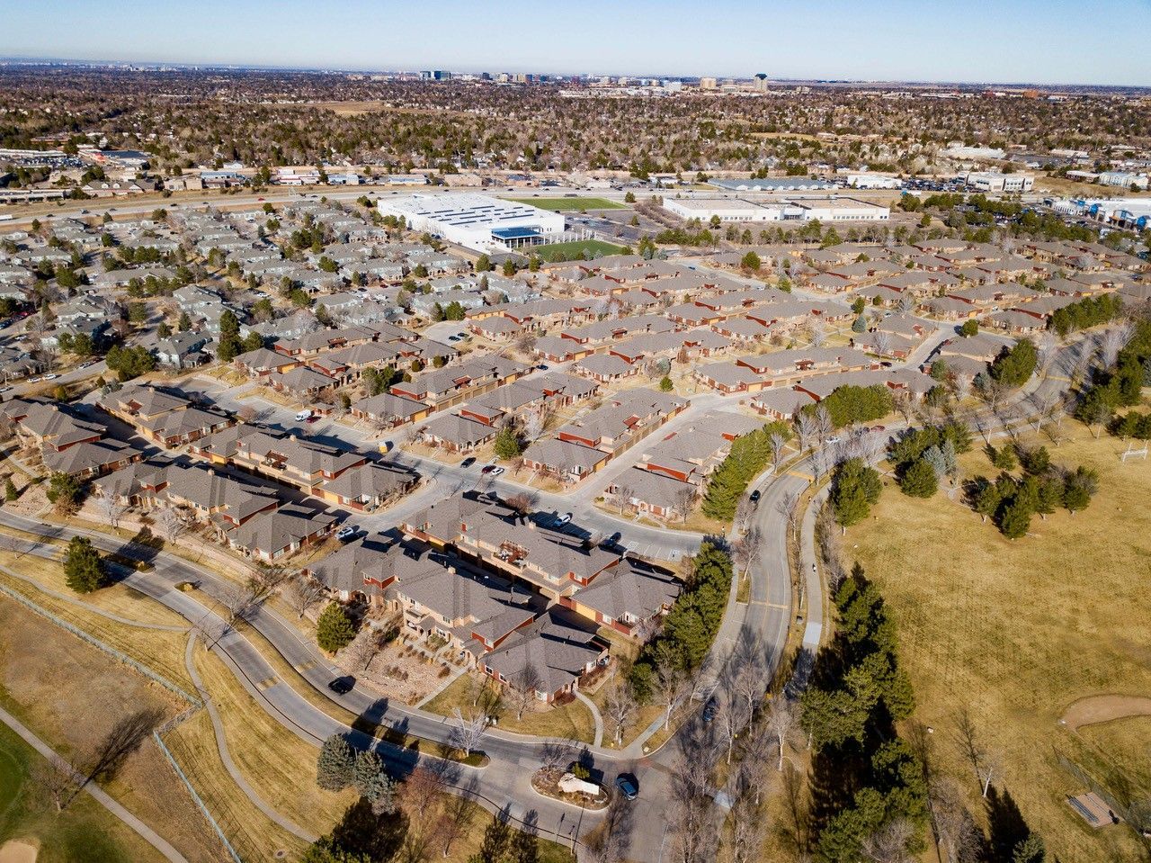 Aerial view of a suburban apartment complex beside open fields and roads.