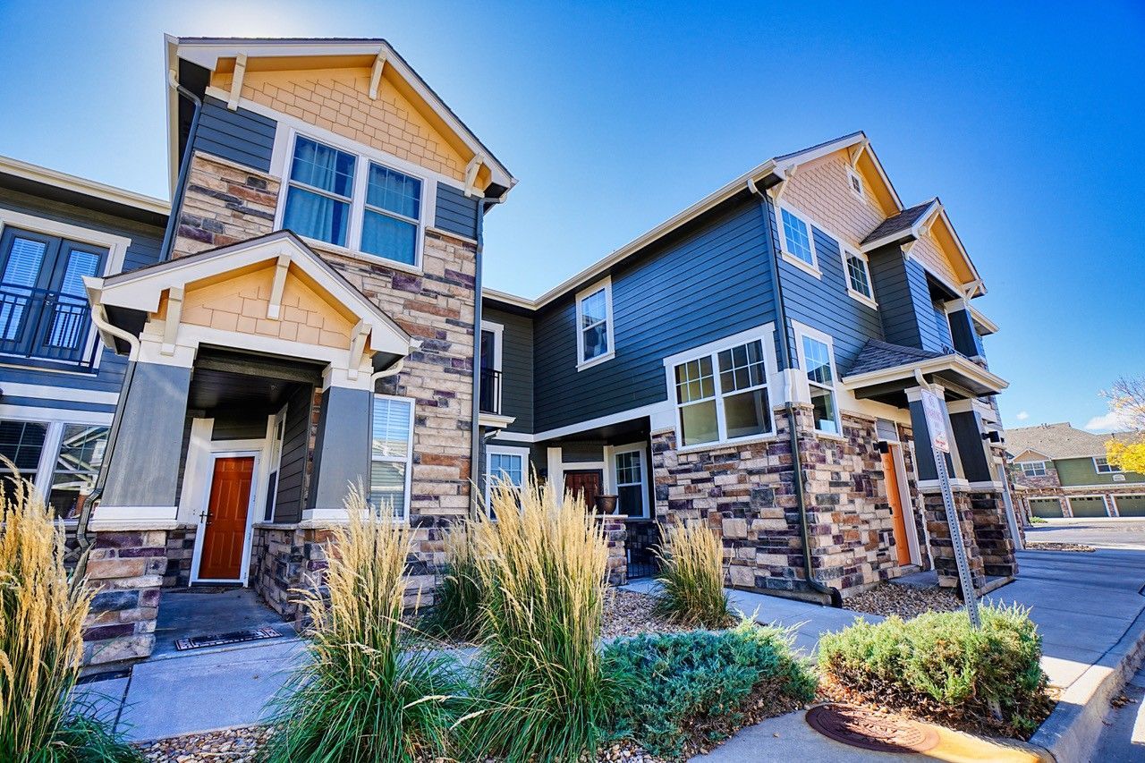Modern two-story suburban houses with stone and dark blue siding under a clear blue sky.