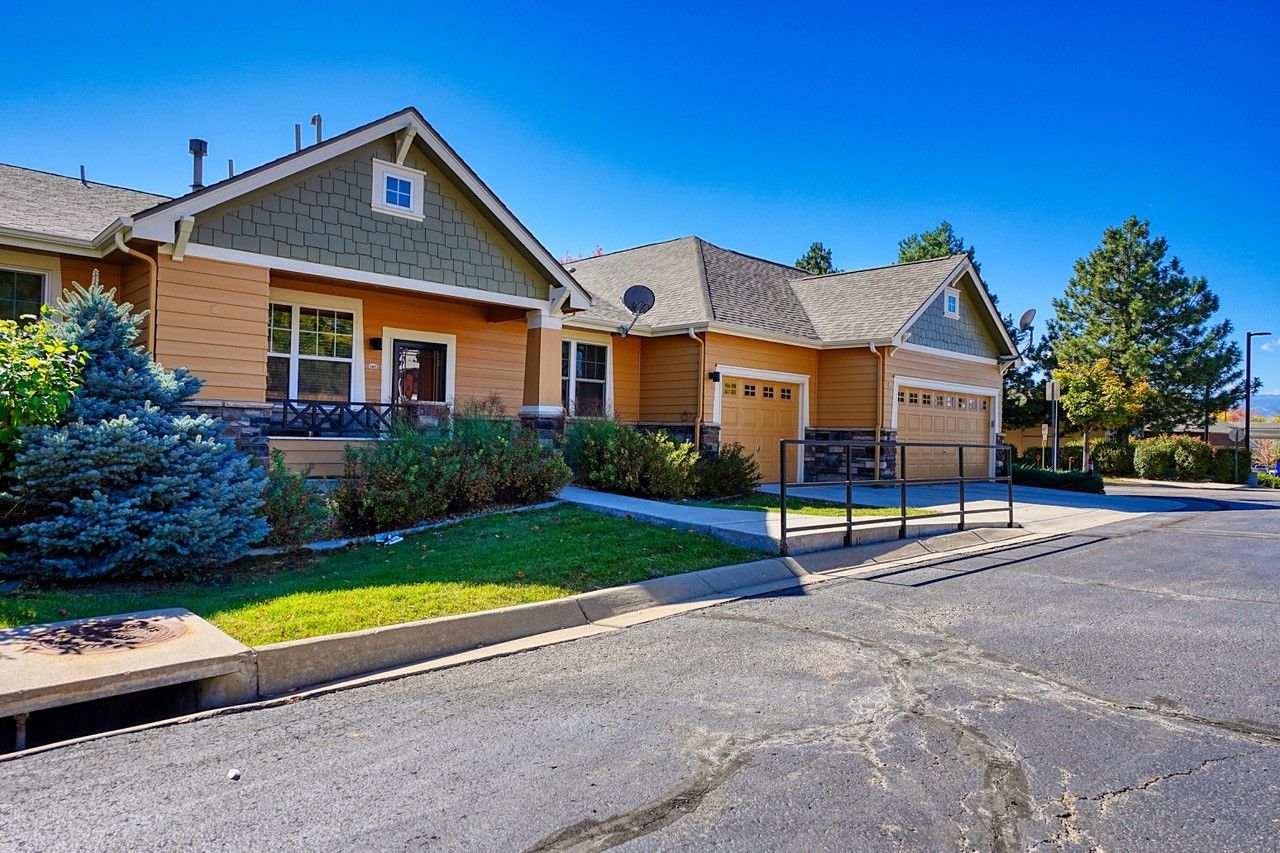 Single-story beige building with garage bays and a blue handicap parking sign on a sunny street.