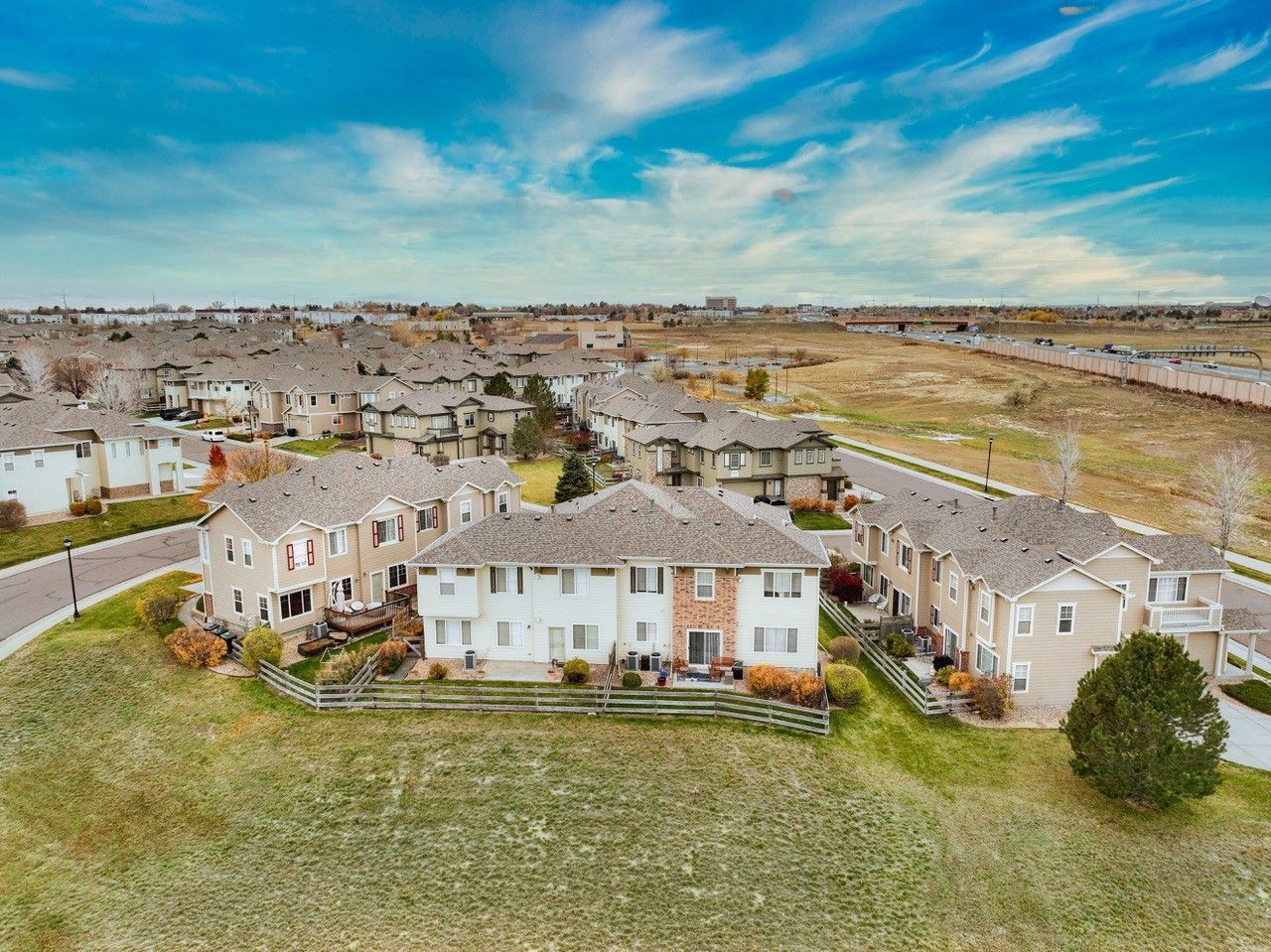 Suburban neighborhood with tan houses under a blue sky, viewed from above.