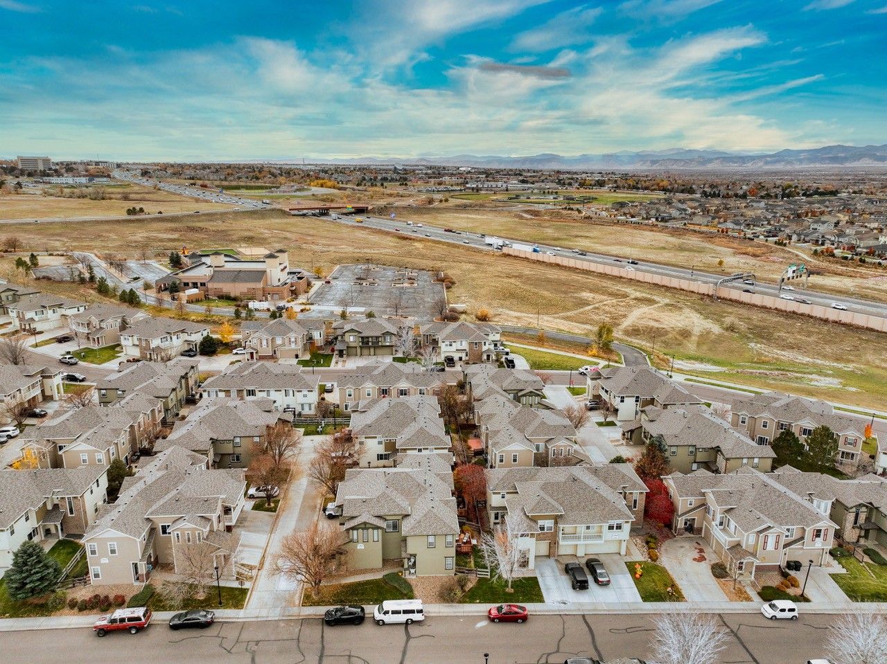 Aerial view of a suburban neighborhood beside a dry river channel under a cloudy sky.
