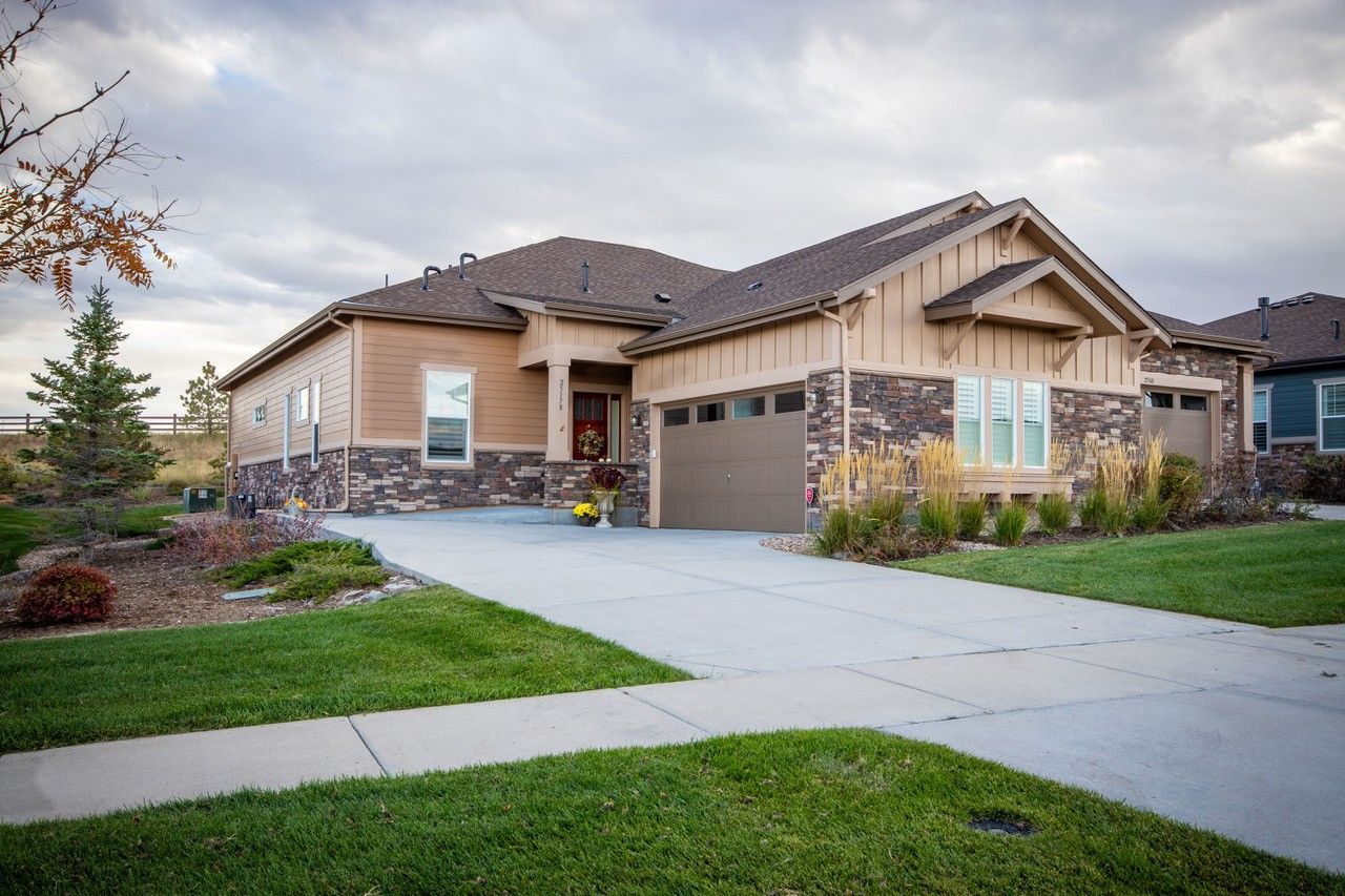 Suburban single-story house with a garage, stone accents, and a driveway in a landscaped front yard.