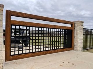 A large, brown wooden gate with a black metal grid, displaying the address