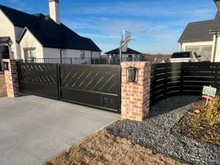Black metal gate with brick pillars, mailbox, and address