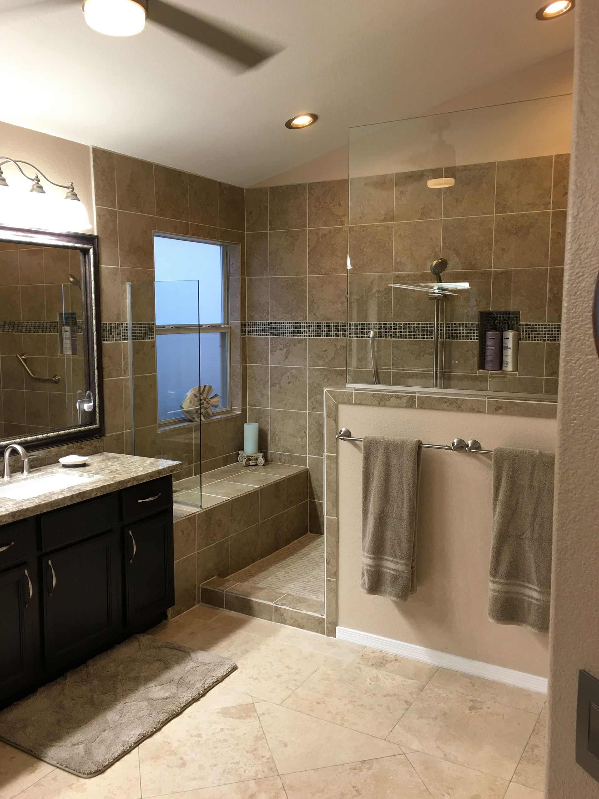 A bathroom with a walk in shower, sink, and mirror.