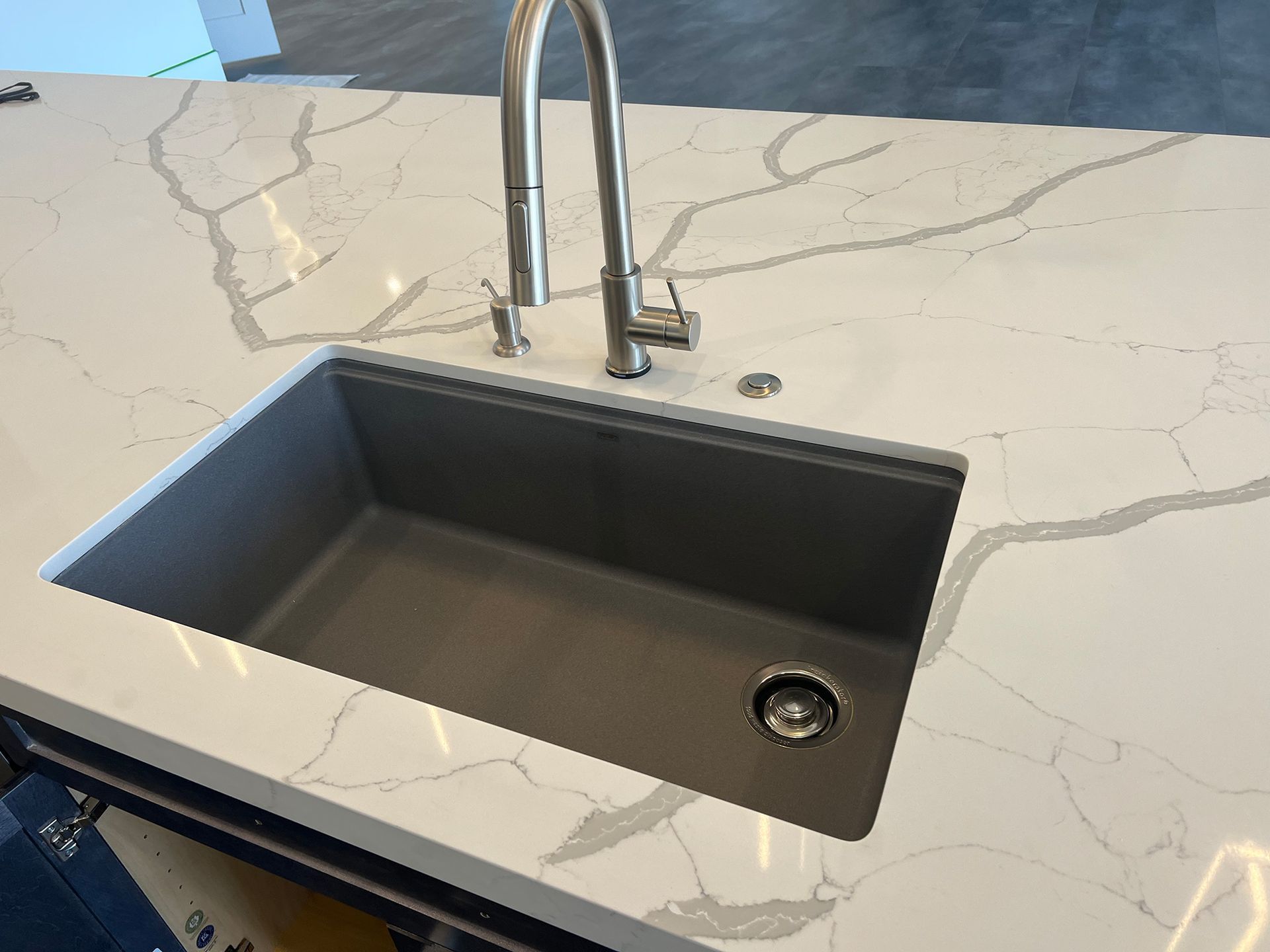 A kitchen sink is sitting on top of a marble counter top.