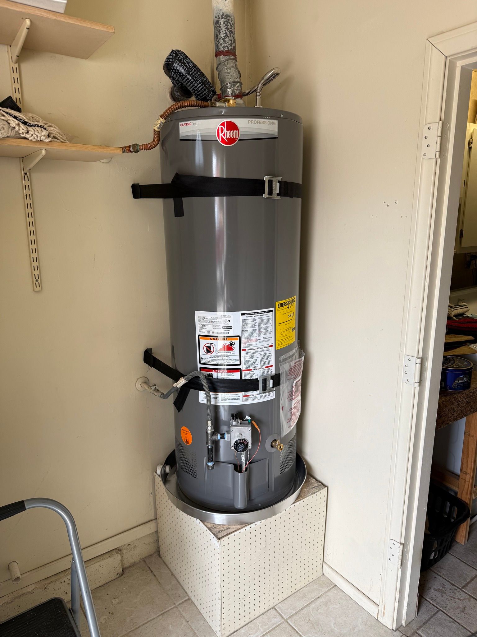 A gray water heater is sitting in a corner of a room.