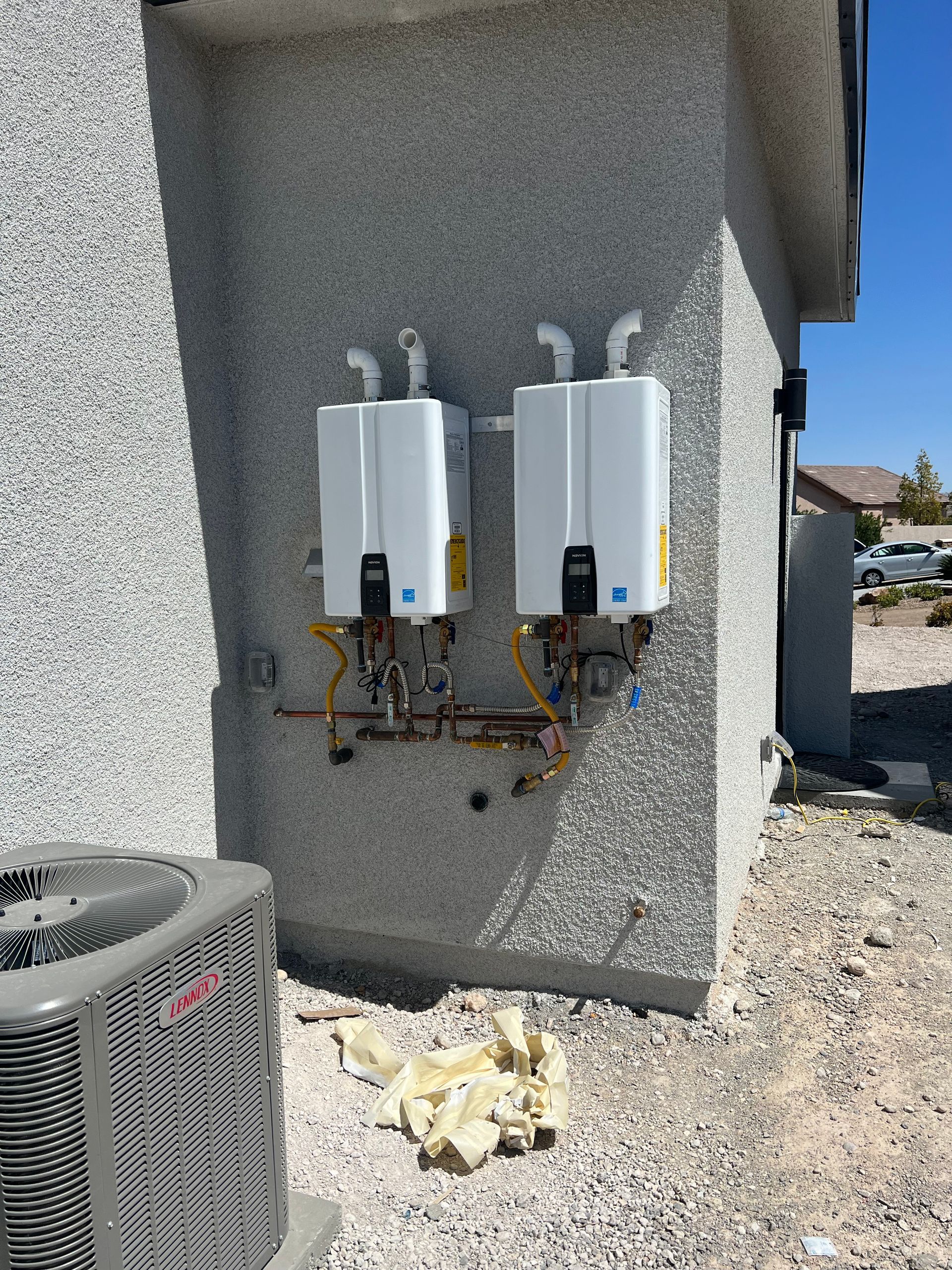 Two water heaters are installed on the side of a building.