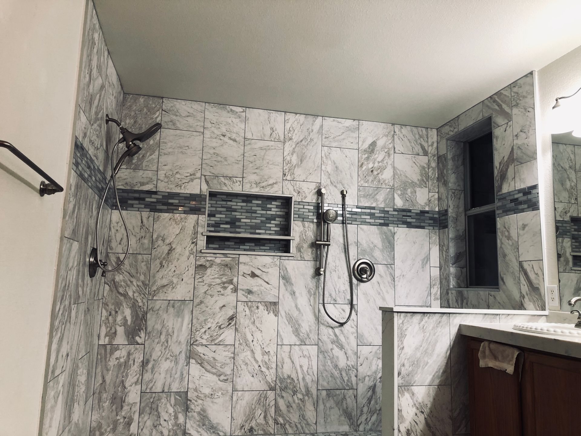A bathroom with a shower , sink and mirror.