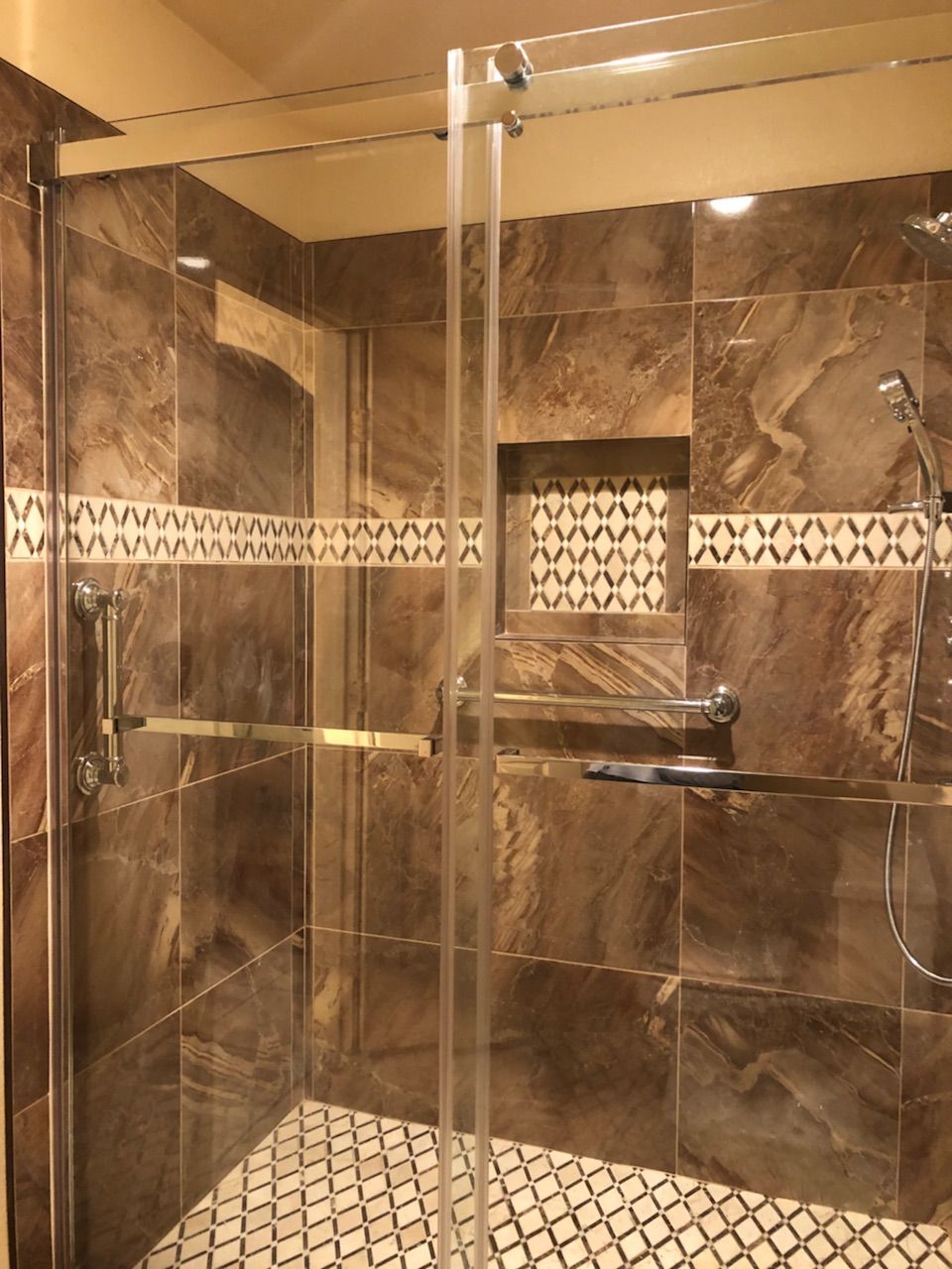 A bathroom with brown tiles and a sliding glass shower door