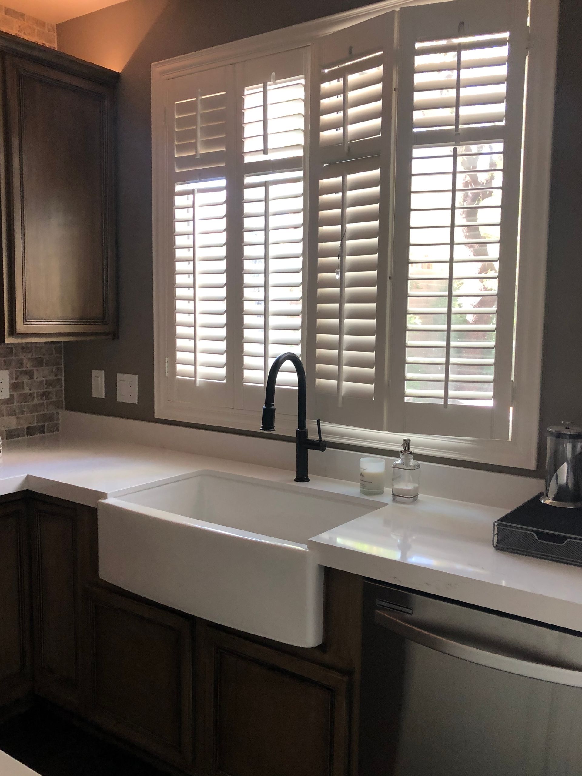 A kitchen with a sink and a window with shutters.
