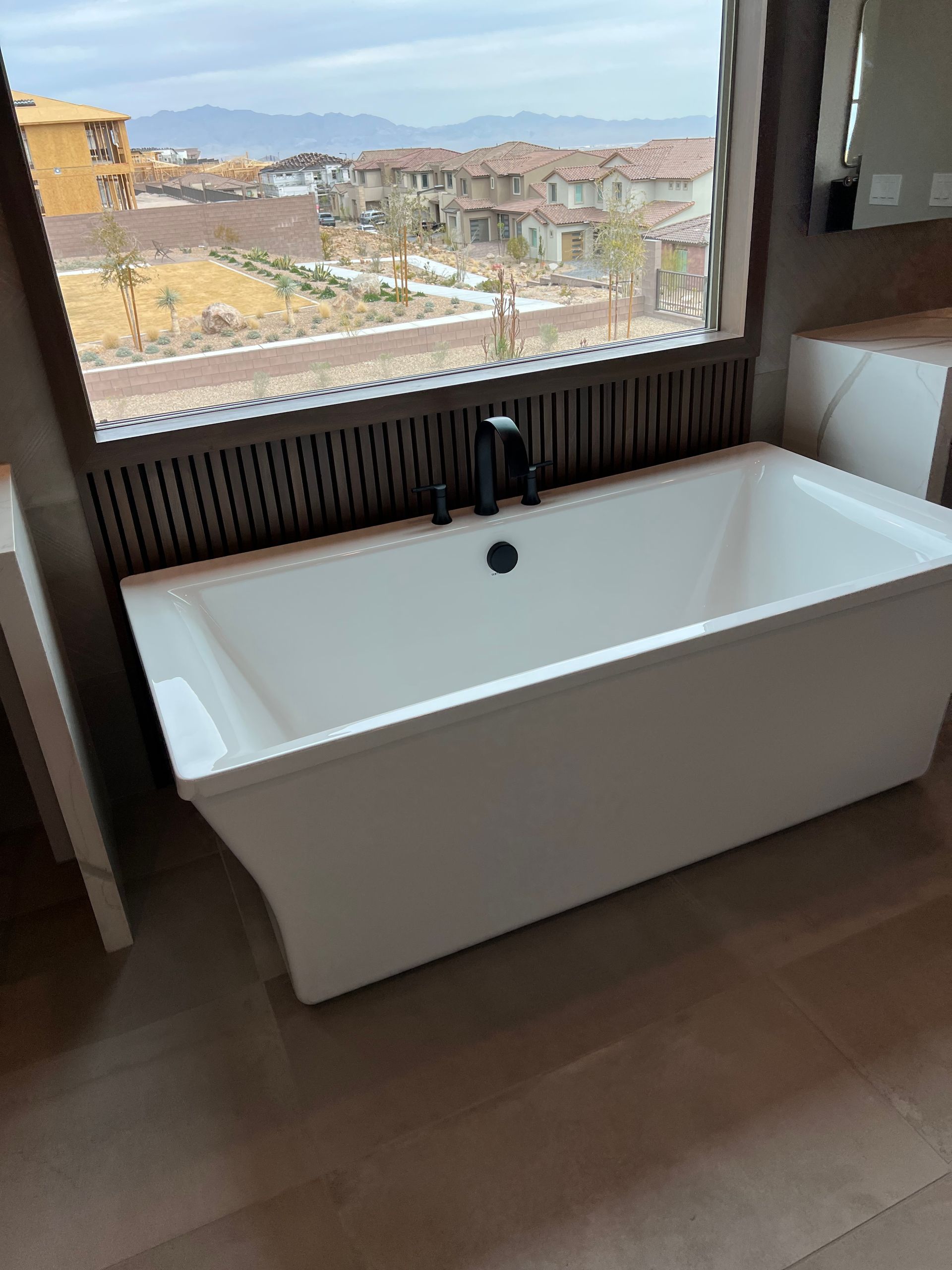 A white bathtub is sitting in a bathroom next to a window.