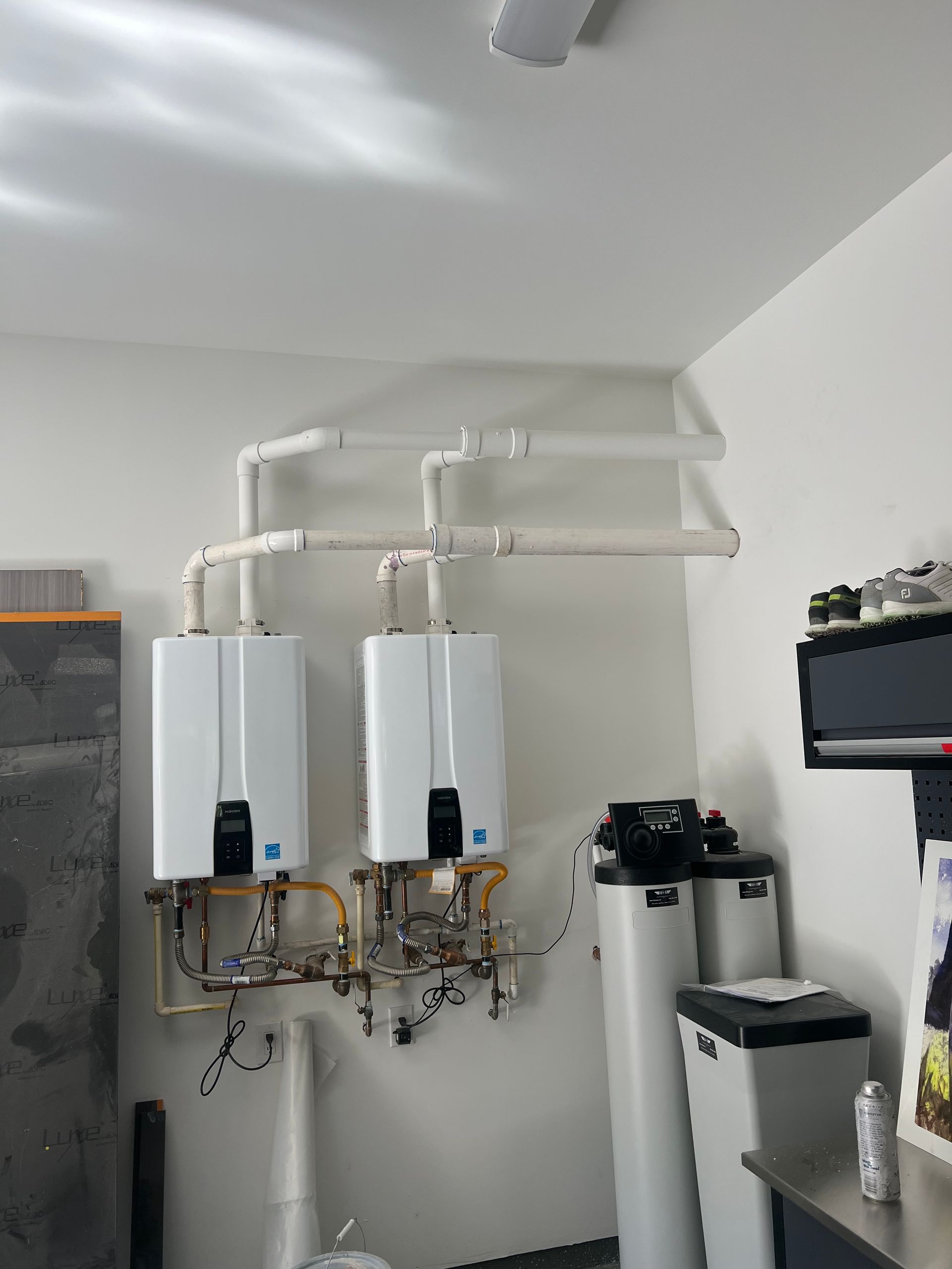 Two water heaters are hanging on the wall in a room.