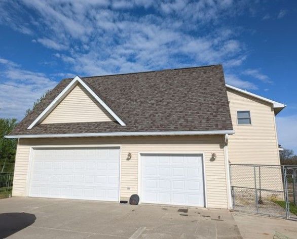 A house with two garage doors and a brown roof