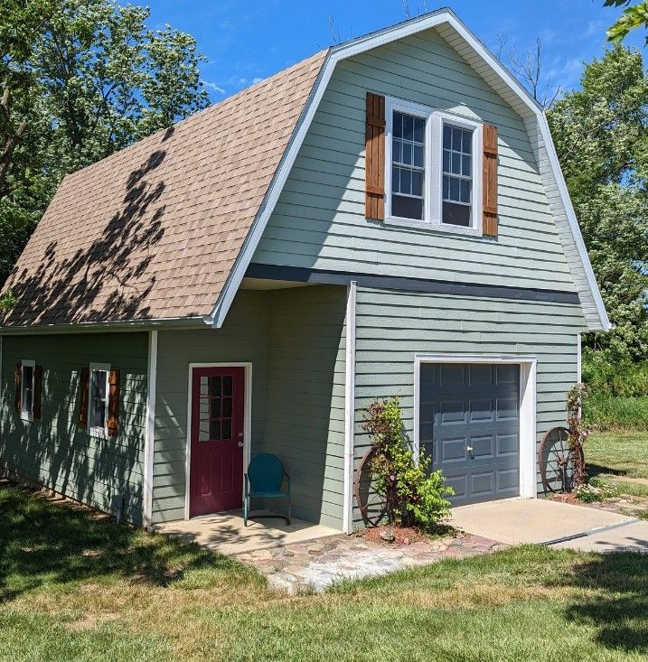 A green house with a garage and a red door