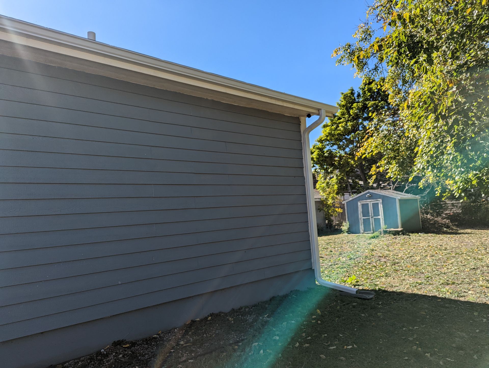 A house with a shed in the backyard and a blue sky in the background