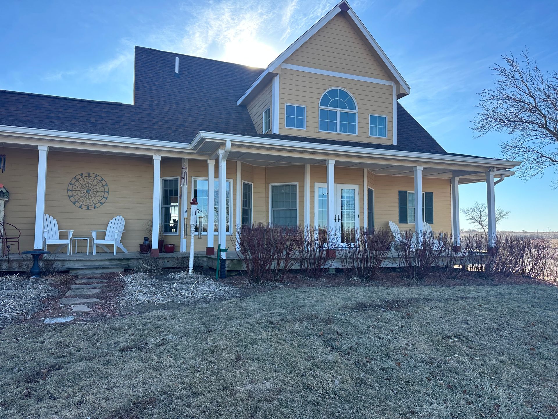 A large yellow house with a porch and chairs on it