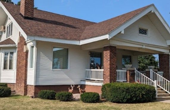 A white house with a brown roof and a porch
