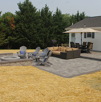 a patio with a fire pit and chairs in front of a house