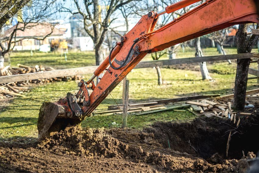 A large orange excavator is digging a hole in the ground.