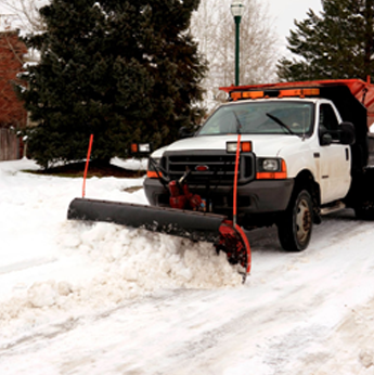 a white truck is plowing snow on a snowy road