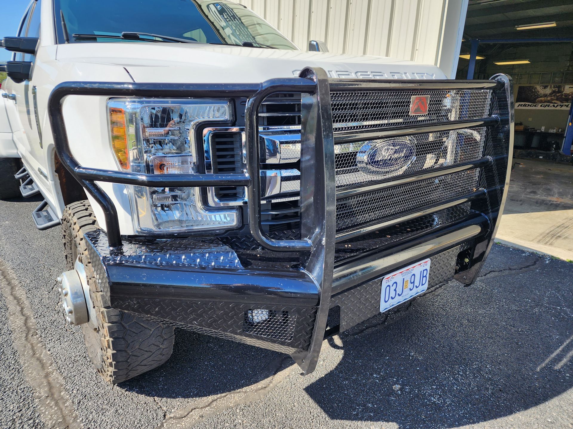 Black pickup truck with a heavy-duty chrome grille guard parked outdoors near a building.