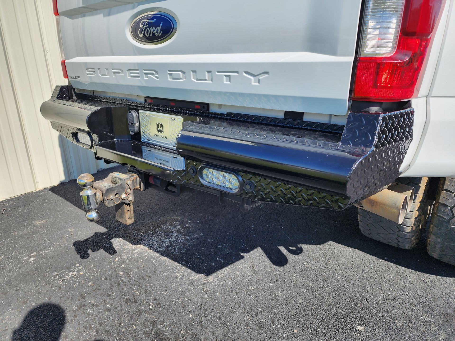 Rear of a silver Ford Super Duty truck with a trailer hitch and bumper-mounted accessories