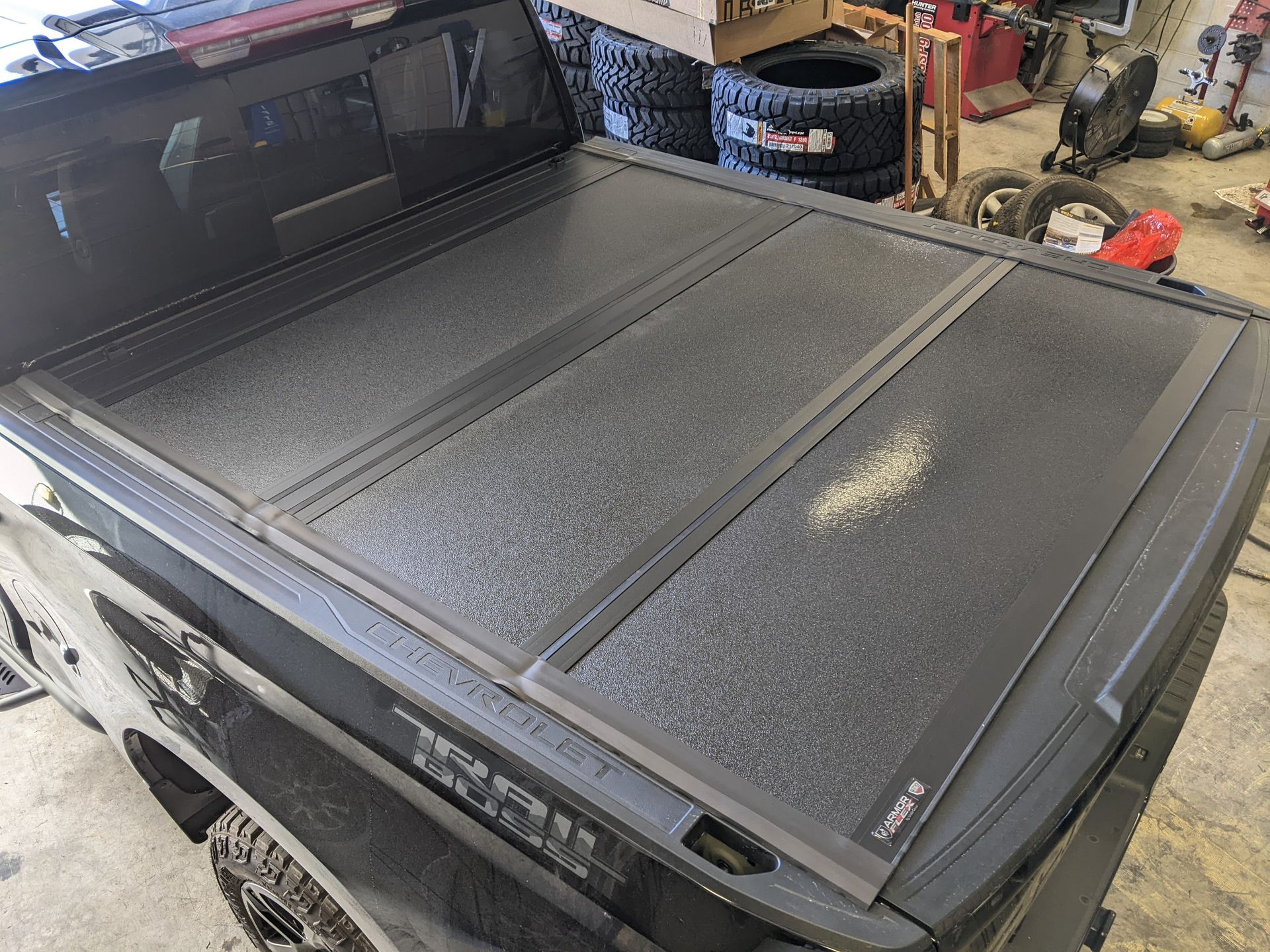 Black pickup truck with a folding hard tonneau cover in a garage, viewed from above