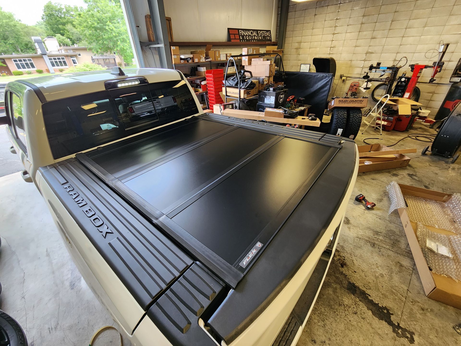 Large black flatbed printer in a cluttered workshop garage