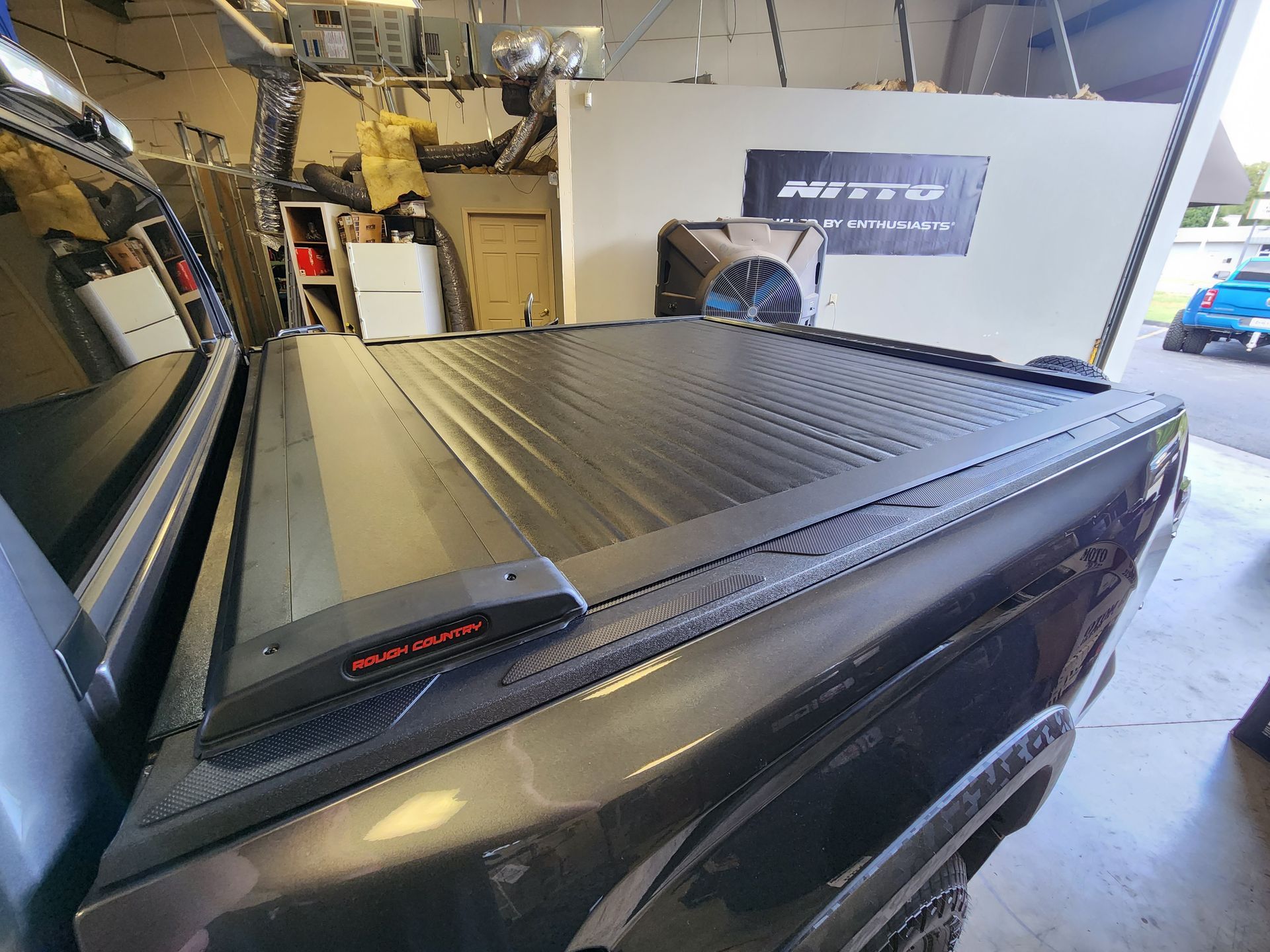 Black pickup truck with a covered bed inside an automotive workshop