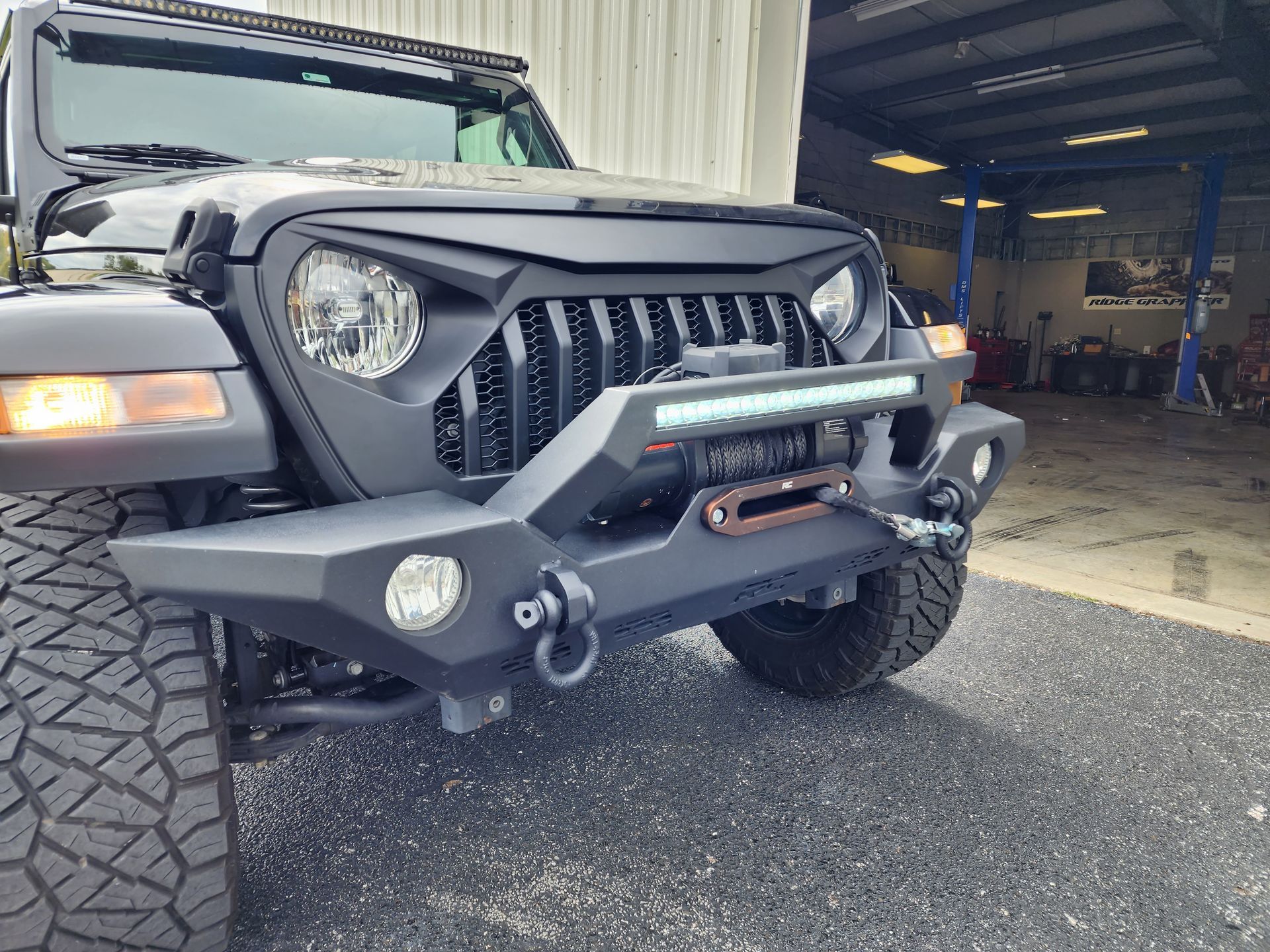Black off-road Jeep with rugged front bumper parked in a garage.