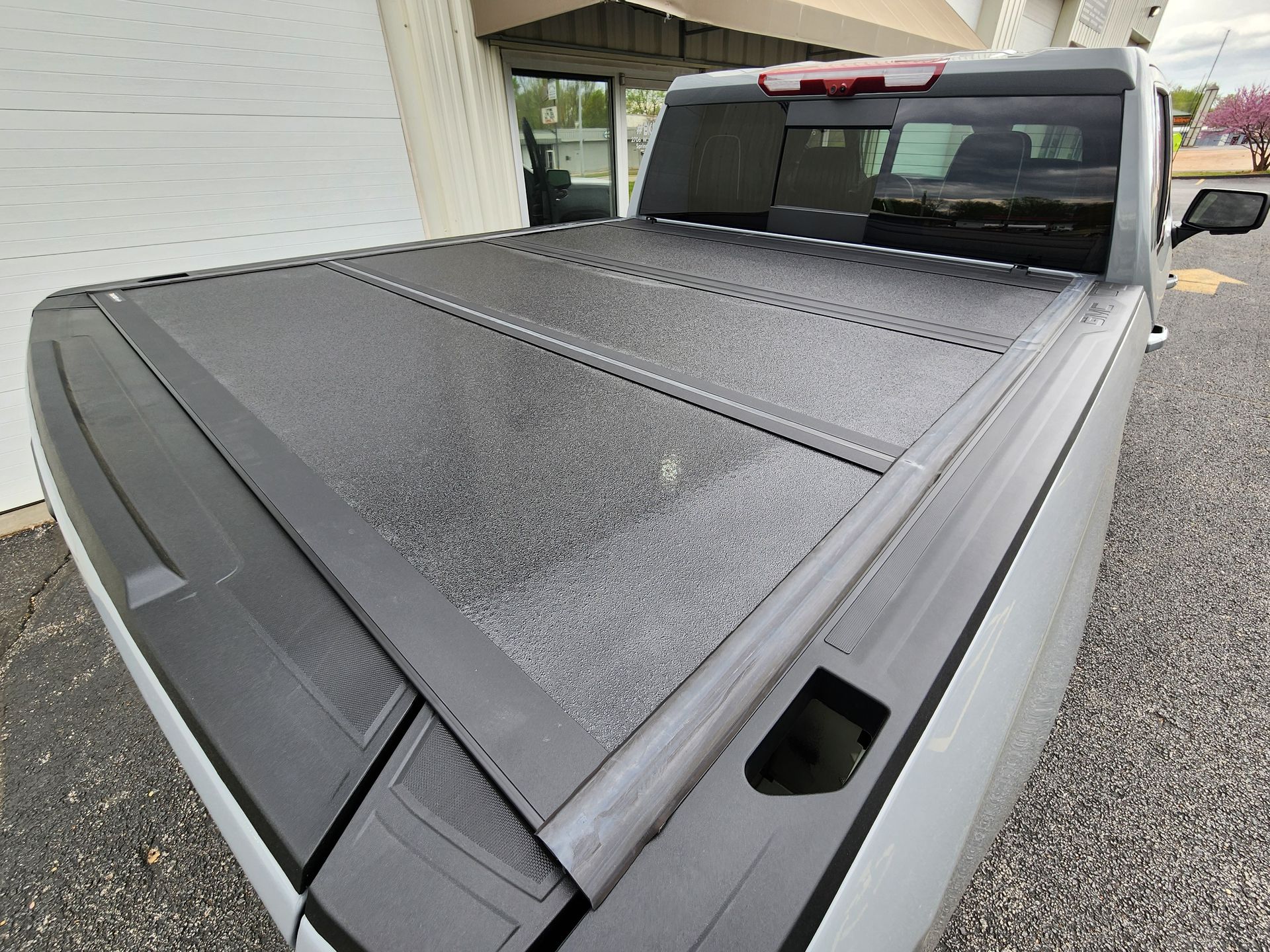 Rain-covered black pickup truck bed cover in a driveway