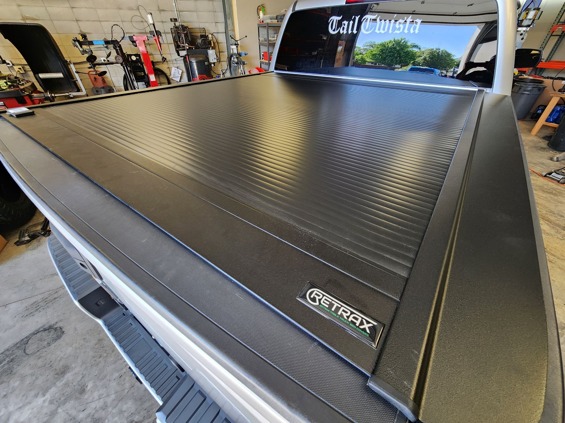 Black pickup truck bed cover with spiral pattern in a workshop garage