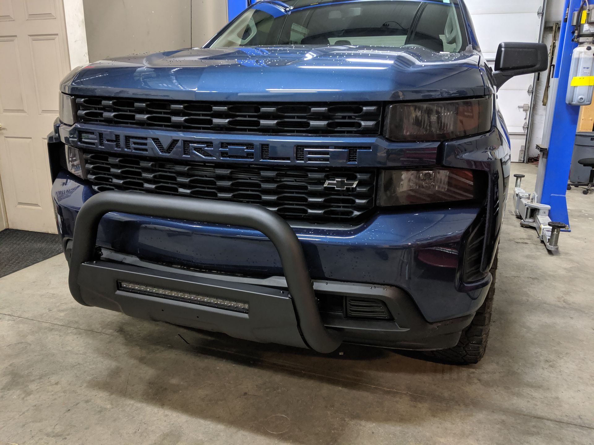 Dark blue Chevrolet pickup truck with a front bumper guard in a garage