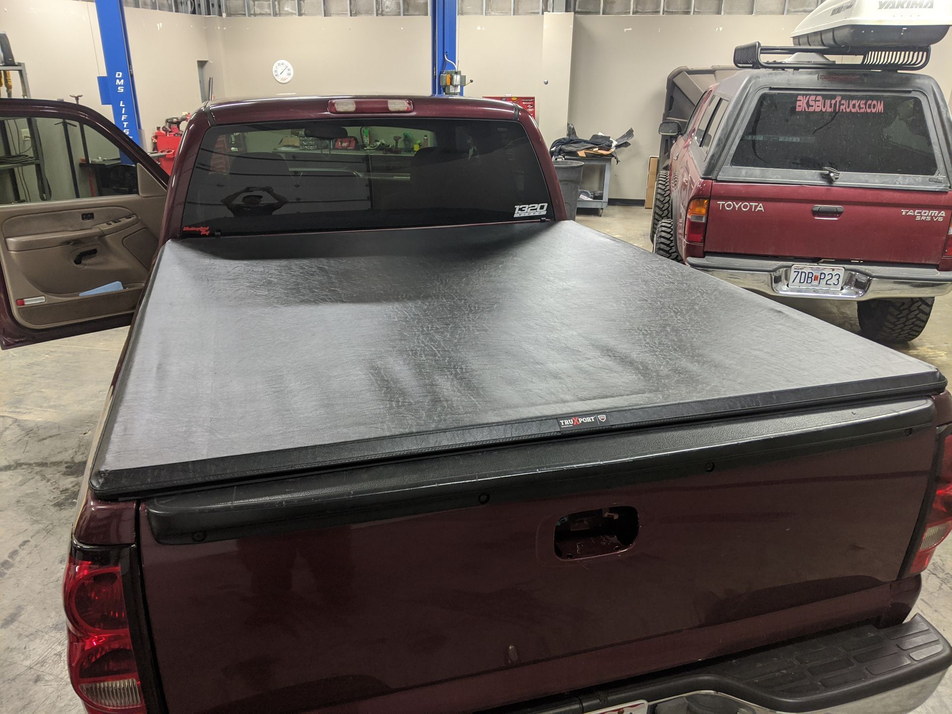 Red pickup truck in a garage with a black tonneau cover on the bed