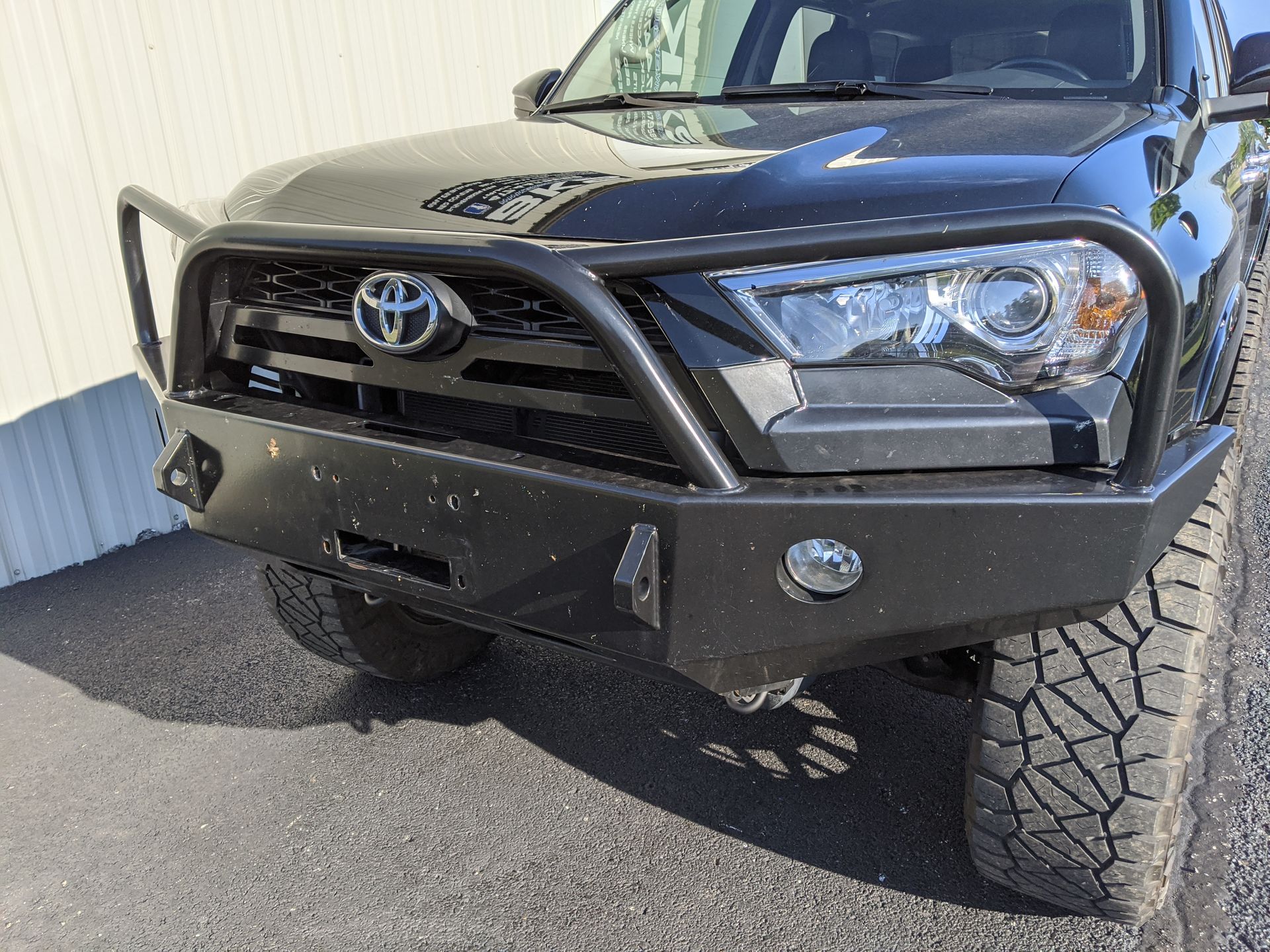 Front view of a black Toyota truck with a heavy-duty bumper and off-road tires