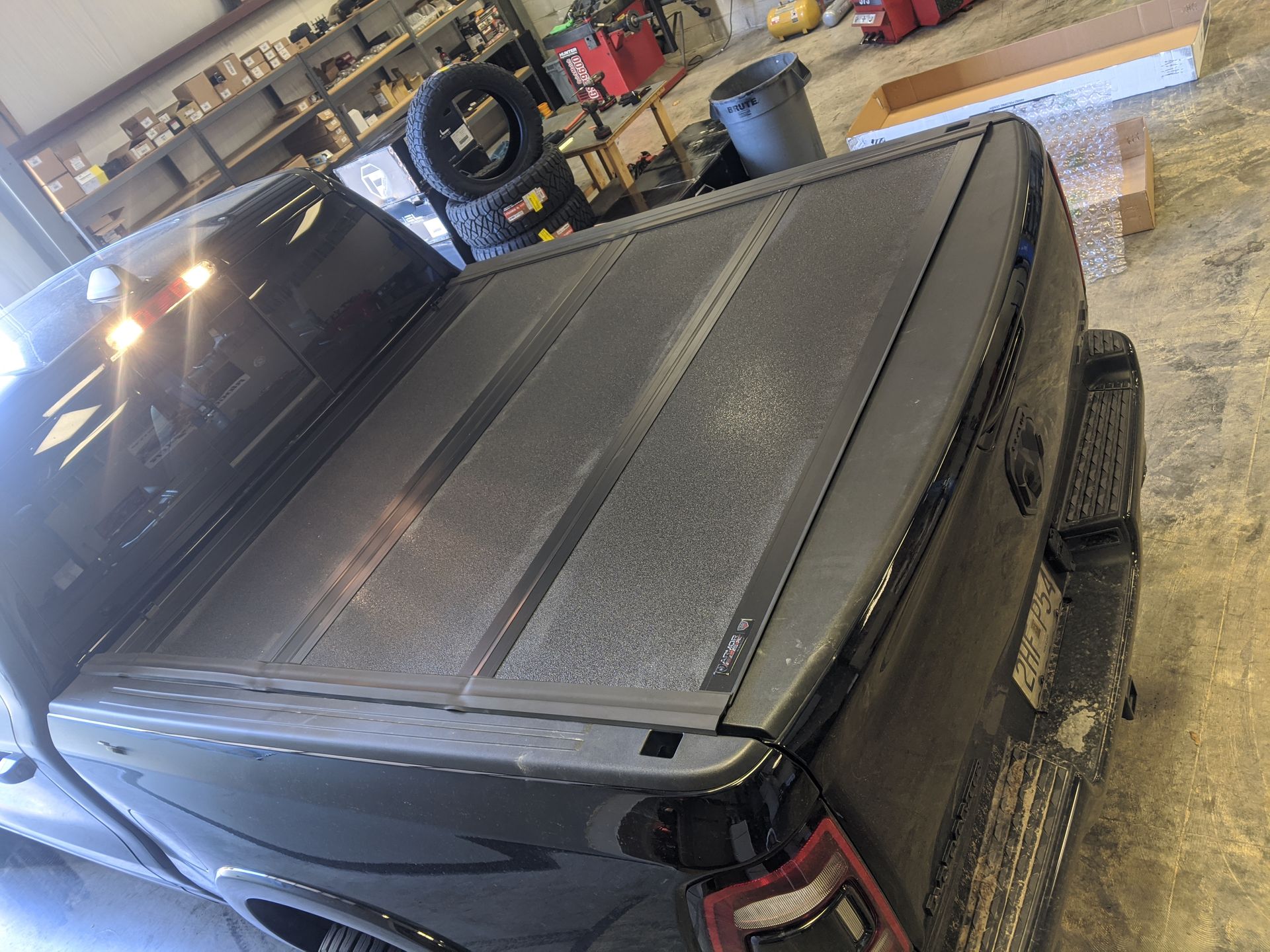 Black pickup truck with a tonneau cover parked in a garage.