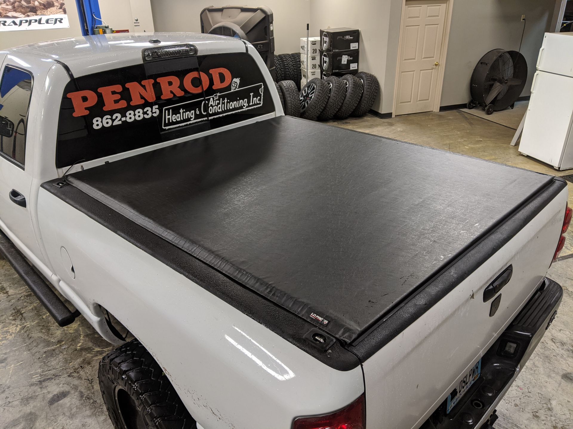 White pickup truck with black bed cover and PENROD service decal in a garage