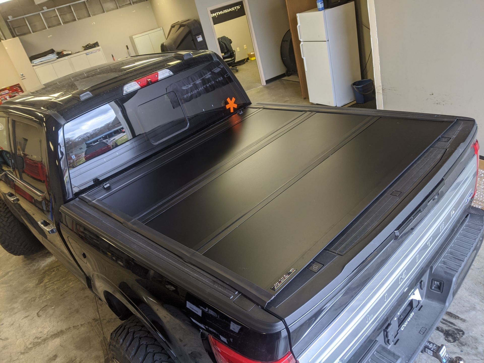 Black pickup truck with a closed bed cover parked inside a garage