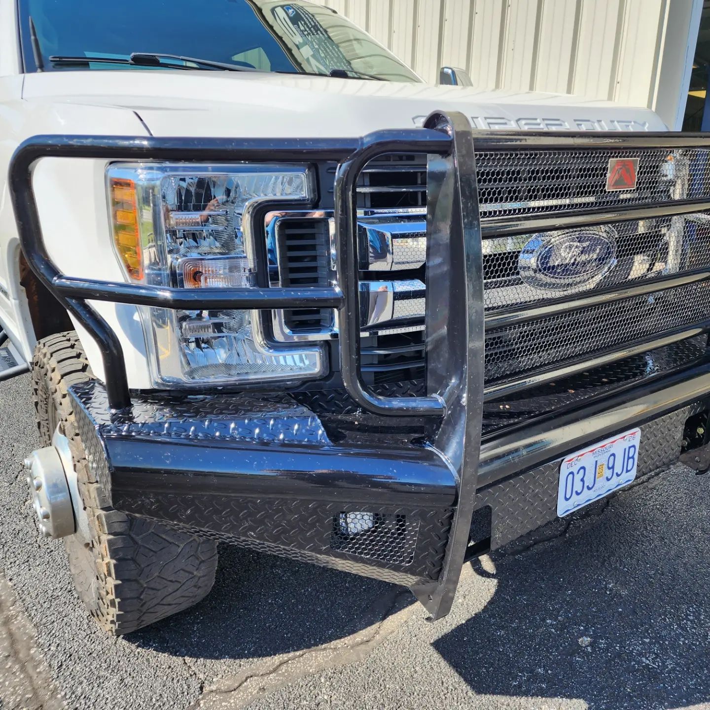 White pickup truck with a black grille guard parked outside a building