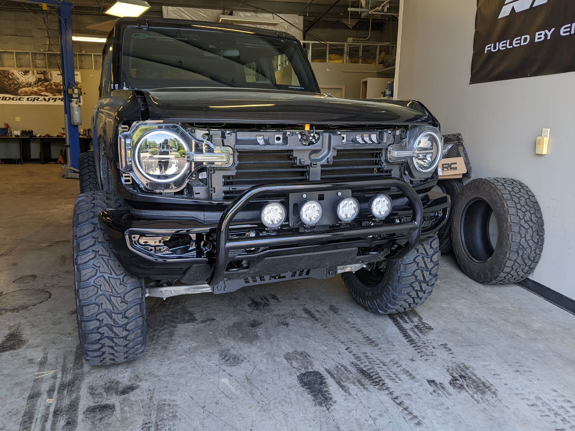 Black off-road SUV in a garage, front view with large tires and auxiliary lights