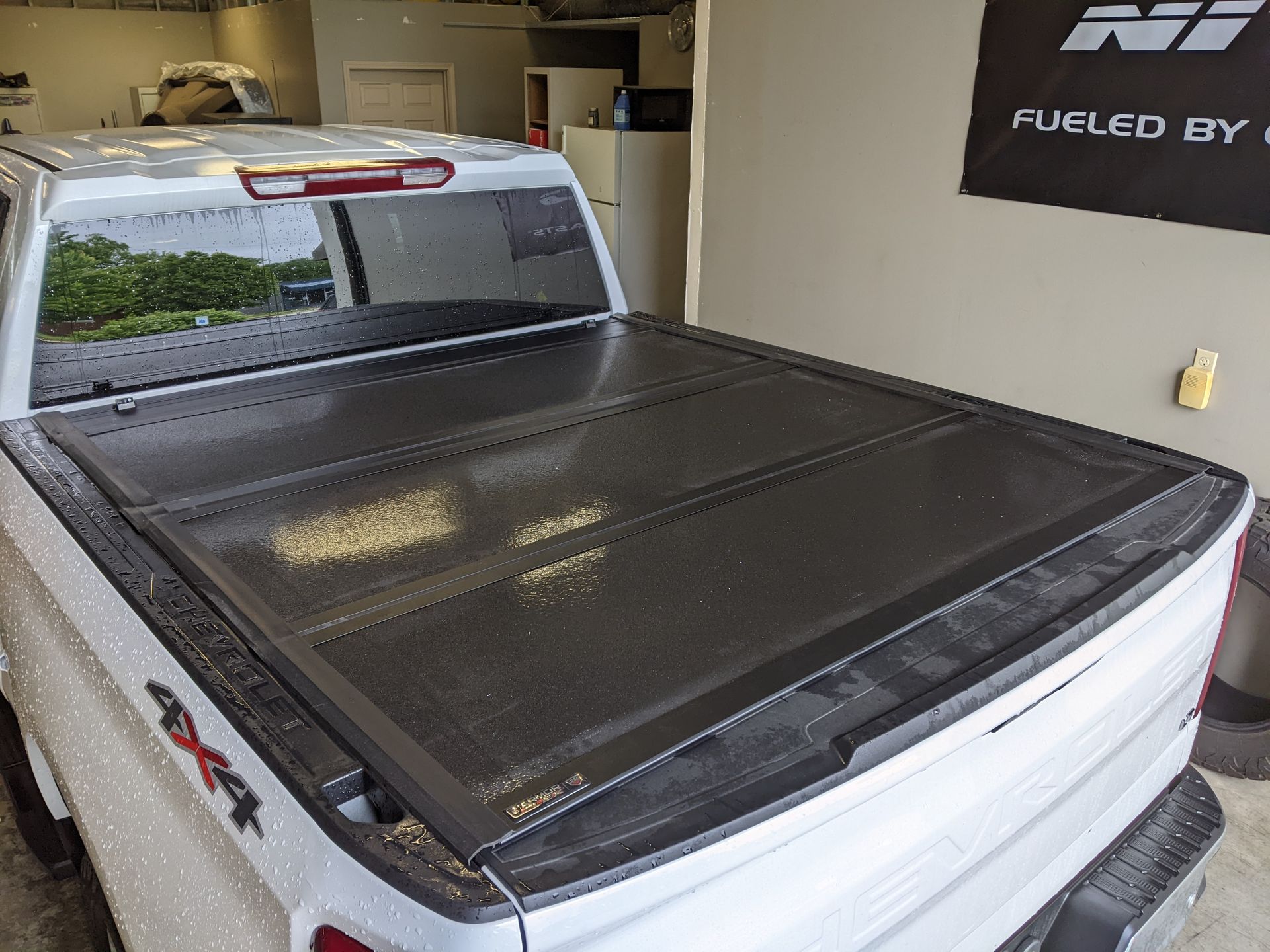 White pickup truck in a garage with a black tonneau cover over the bed