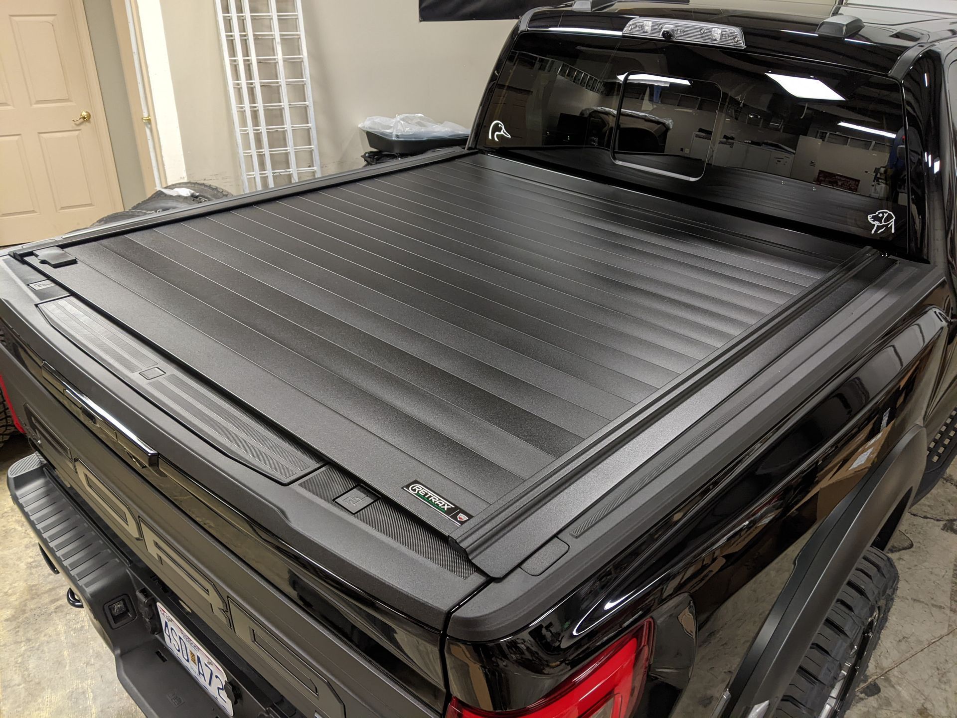 Black pickup truck with a closed hard tonneau cover in a garage
