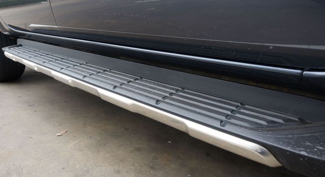 Close-up of a black truck’s side step running board with silver trim and textured tread.