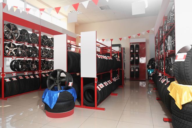 Interior of a tire shop with rows of black tires, red shelves, and hanging red-and-white bunting